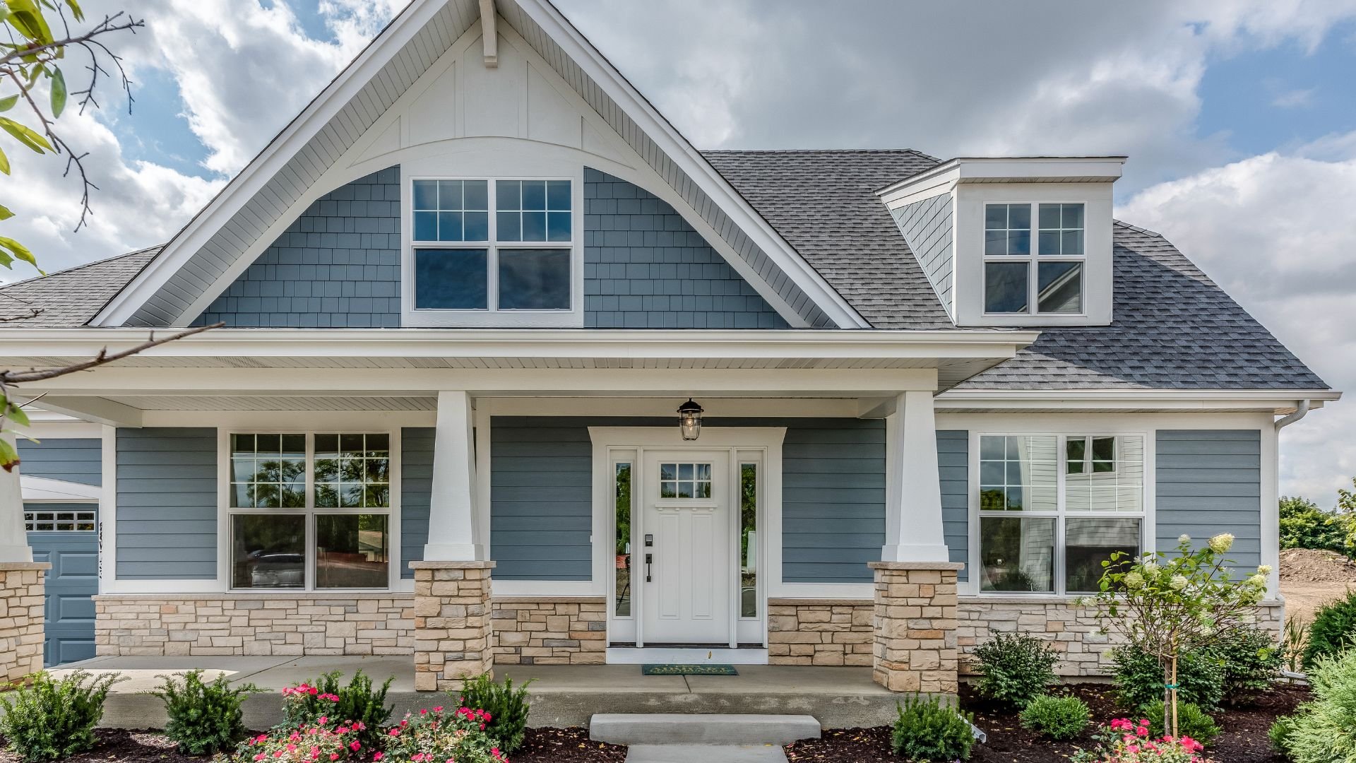 Craftsman-style blue and white house with stone foundation and front porch