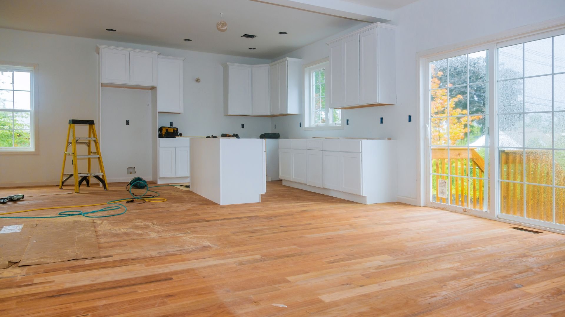 Kitchen renovation in progress with white cabinets and wooden floors