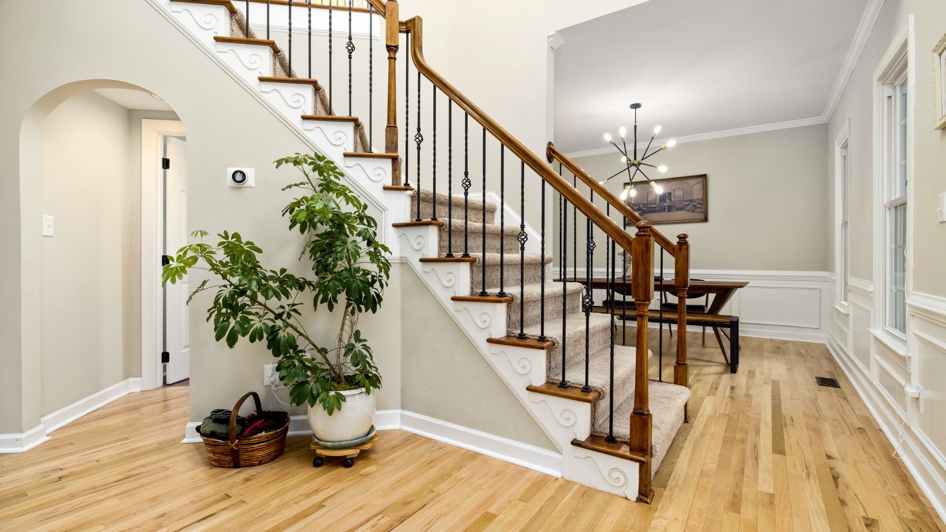 Elegant interior with wooden staircase, iron railings, and potted plant