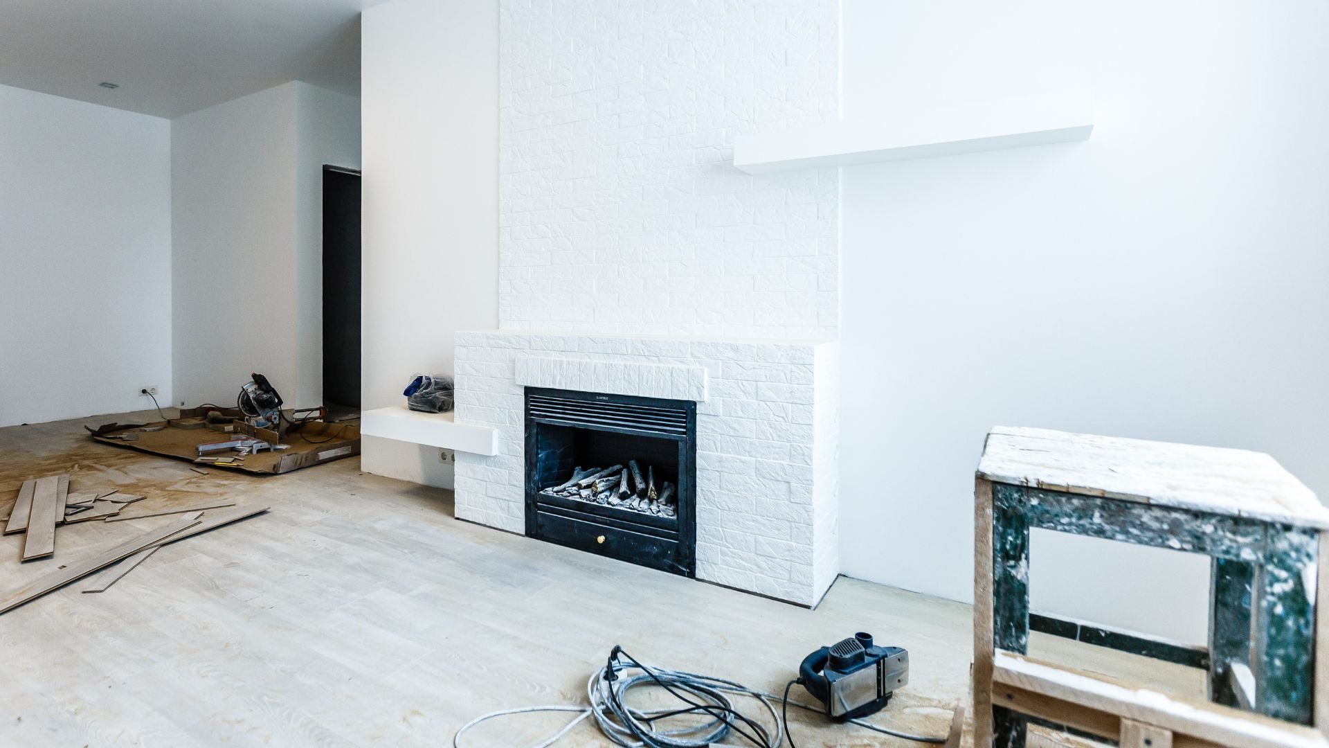 Home renovation in progress with white fireplace and scattered construction tools